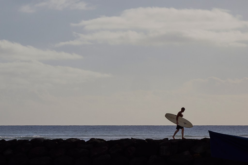 Following his surfing adventure at Kaisers this surfer negotiated the rock piling to return to his car and head home on Friday January 17th. (David Croxford/Civil Beat/2025)