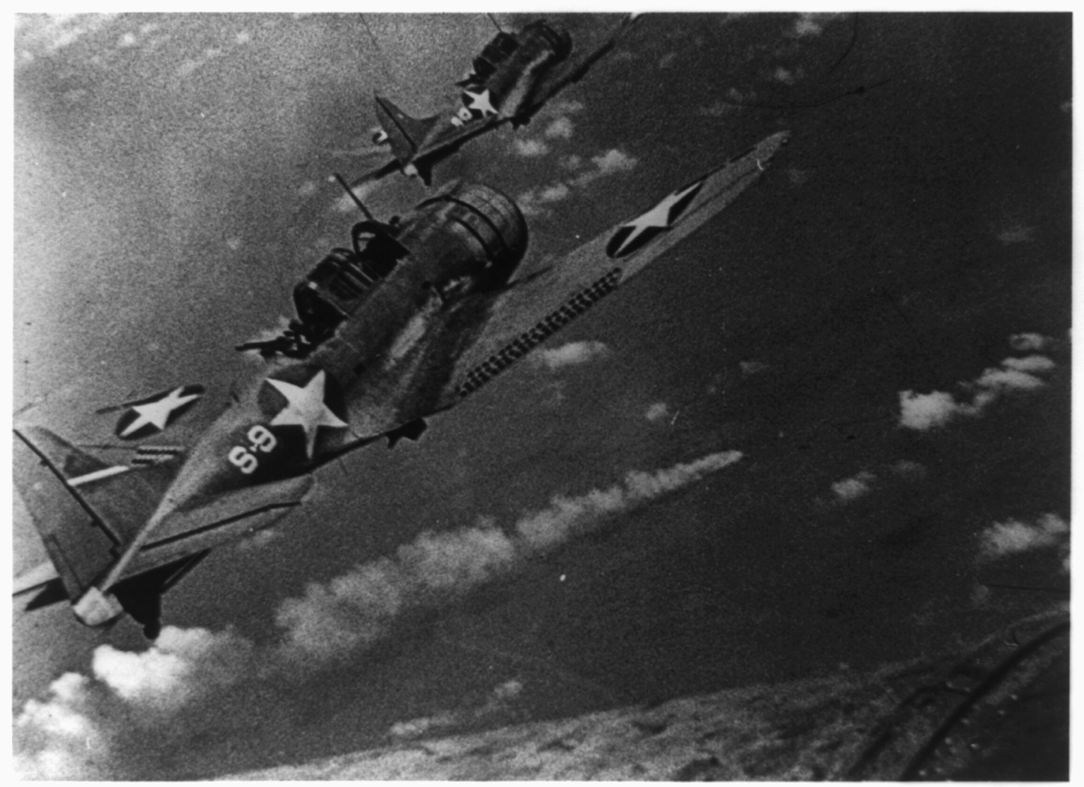 Aerial view of U.S. Navy fighter planes during the attack on the Japanese fleet off Midway, and burning Japanese ship below.