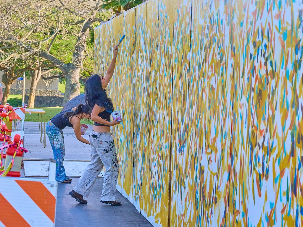 On the First Friday of February (2.7.25), Artist Solomon Enos paints lei on a construction barrier at the State Capitol assisted by members of the public who added their personal touches to the mural. (David Croxford/Civil Beat/2025)