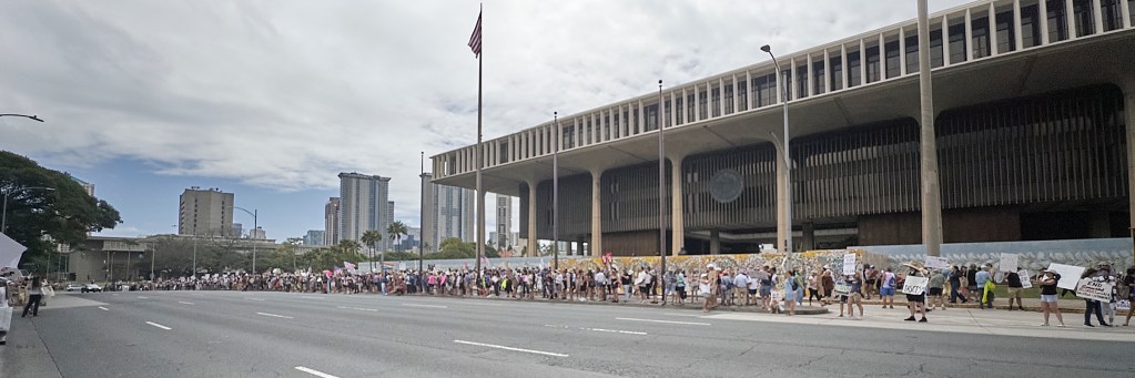 While most of Hawaii celebrated President’s Day 2025 spending time with their families, a vocally confrontational crowd crooned their opposition to President Trump’s attempts, with the help of Elon Musk, to follow through on President Obama’s Executive Order 13576 signed on June 13th 2011 whose thrust was to deliver an Efficient, Effective, and Accountable Government.
(David Croxford/Civil Beat/2025)