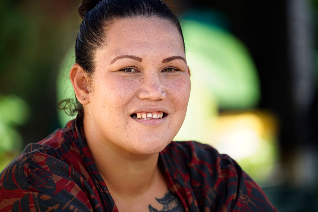 Simoné Nanilei Kamaunu is photographed Tuesday, Feb. 18, 2025, in the backyard of her Māʻili home in Waiʻanae. The Department of Corrections and Rehabilitation’s offer to help those incarcerated obtain identification cards like birth certificates, social security cards and Hawaiʻi state ID cards have been slow. Kamaunu continues to wait for some of the IDs she needs for work since her release. In the meantime, her love of the ʻāina continues to bloom while she continues to study, do homework and raise keiki. (Kevin Fujii/Civil Beat/2025)