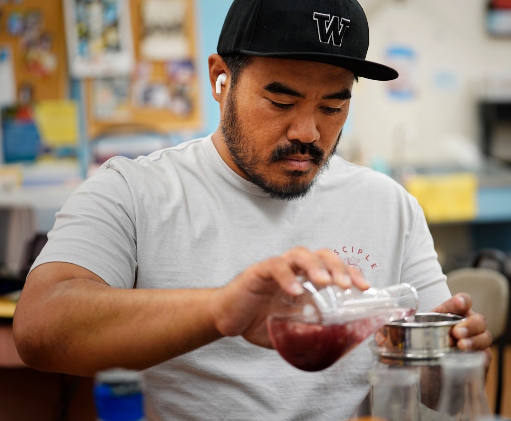 Tyson Arasato, a 2007 Waiʻanae High School graduate of the Marine Science Learning Center program, changes the water for young limu Monday, April 21, 2025, in Waiʻanae. Arasato now teaches Career Technical Education (CTE) four levels of the program’s education sequence. The program uses another name for their limu: ogo. (Kevin Fujii/Civil Beat/2025)