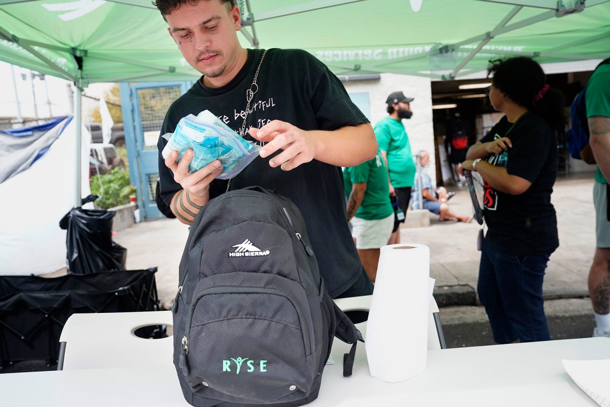 Brody Craig, 21, loads his backpack to hand out pet food, toiletries, laundry detergent, meals and drinks at Pūnawai Rest Stop with RYSE Friday, April 25, 2025, in Honolulu. (Kevin Fujii/Civil Beat/2025)