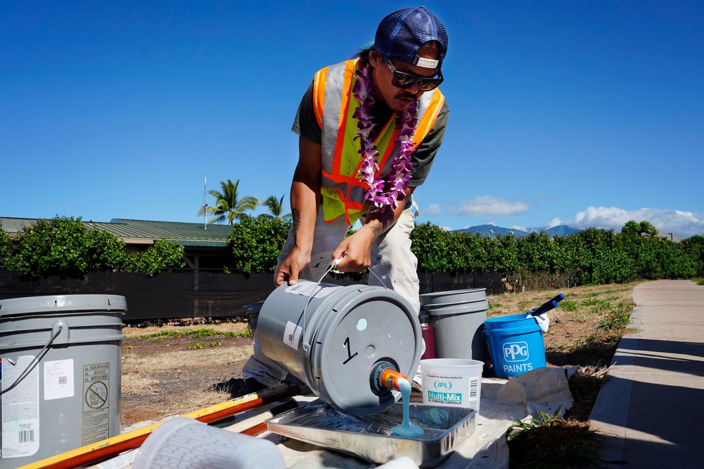 South Maui “Quick Build” project artists Matt Agcolicol pours the first paint for community volunteers to use at the intersection of Kenolio Road and Alulike Street Saturday, May 3, 2025, in Kīhei. The Maui Metropolitan Planning Organization says painting a street mural will bring color and safety to this busy residential corridor. (Kevin Fujii/Civil Beat/2025)