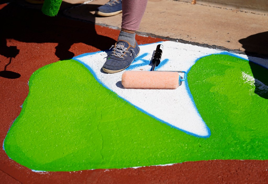 A fresh roller waits for a volunteer painter to fill in the No. 14 color at the intersection of Kenolio Road and Alulike Street Sunday, May 4, 2025, in Kīhei. The Maui Metropolitan Planning Organization says painting a street mural will bring color and safety to this busy residential corridor. (Kevin Fujii/Civil Beat/2025)
