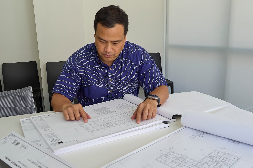 Grant Chang of Lowney Architects reviews plans for a development in their offices in Chinatown. (David Croxford/Civil Beat/2025)