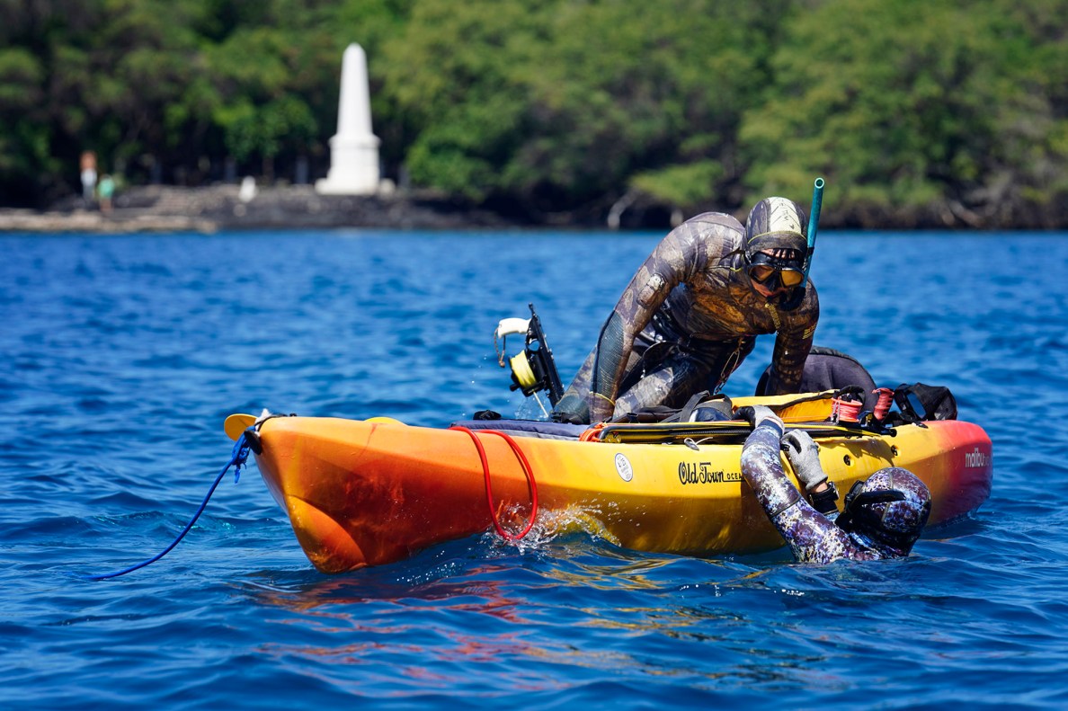 A spearfishing team mounts their kayak during the Kealakekua Bay Non-Native I‘a (fish) Removal Event Sunday, May 18, 2025, in Captain Cook. The event closed Kealakekua Bay waters to other ocean activities which includes tourism. It’s rare to see the Captain Cook monument at Ka'awaloa without tour boats and hoards of tourists snorkeling in water. (Kevin Fujii/Civil Beat/2025)