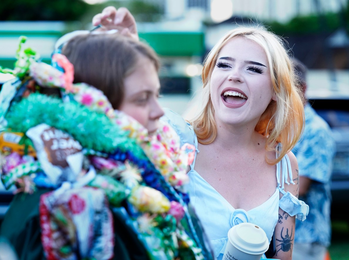 The Hawaiʻi School for the Deaf and Blind graduate Tessie Radl, left, gets help with her leis from her sister Sadie Radl after the graduation ceremony Wednesday, May 28, 2025, in Honolulu. The Radl family lives on the Big Island. Tessie boards at the school on Oʻahu. (Kevin Fujii/Civil Beat/2025)