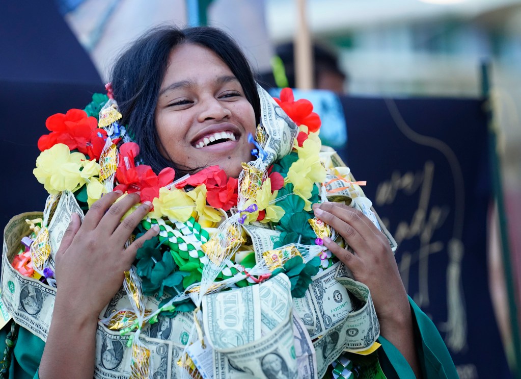Hawaiʻi School for the Deaf and Blind graduate Thanicia Gideon laughs at the weight of all the leis family and friends gave her Wednesday, May 28, 2025, in Honolulu. (Kevin Fujii/Civil Beat/2025)