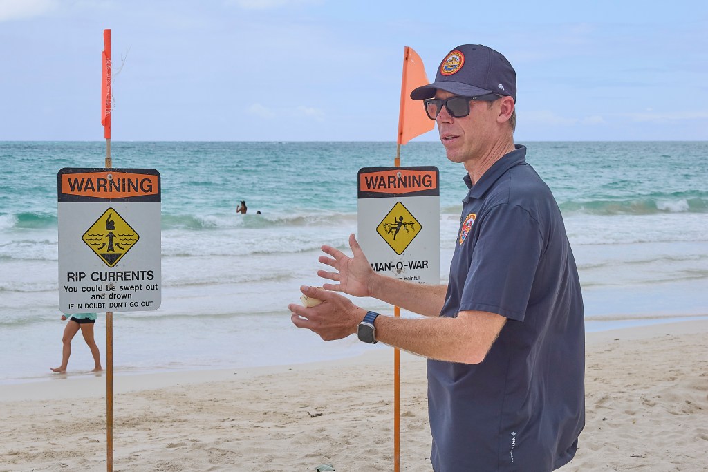 Kurt Lager, Honolulu City and County Ocean Safety Director is photographed at Kalama Beach Park in Kailua where typical safety signs warned of hazardous conditions that beach-goers seemed to ignore as they frolicked in the ocean.(David Croxford/Civil Beat/2025)