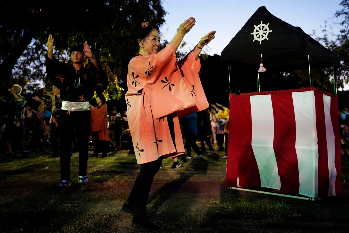 Oʻahu District Bon Dance Club’s Austen Andrade, left, and Gail Takeuchi lead revelers during the first Bon Dance of the season Saturday, June 7, 2025, at Hawaii’s Plantation Village in Waipahu. The summer Obon season is a Japanese Buddhist tradition to celebrate life and honor ancestors. (Kevin Fujii/Civil Beat/2025)