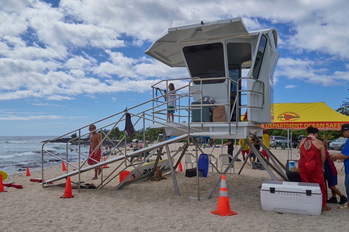 Rachel Able whose daughter drowned at Pine Trees Beach before the Lifeguard  Tower was installed is joined by members of the council and representatives from the mayors office as the tower is blessed on Friday June 13th.(David Croxford/Civil Beat/2025)