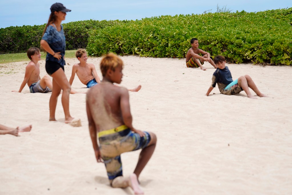 Honolulu Ocean Safety Department’s Junior Lifeguard Program participants sit “frozen” during a game of “Capture the Flag” during its weeklong program at Ko’olina Wednesday, June 25, 2025, in Kapolei. (Kevin Fujii/Civil Beat/2025)