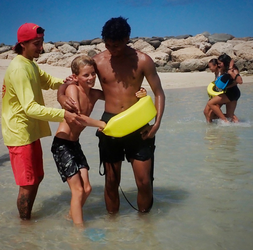Honolulu Ocean Safety Departmen lifeguard Tanner Williams shows Junior Lifeguard Program participants Ezra Fritz, 10, how to rescue someone taller like Isaiah Smith, 16, at Ko’olina Thursday, June 26, 2025, in Kapolei. (Kevin Fujii/Civil Beat/2025)