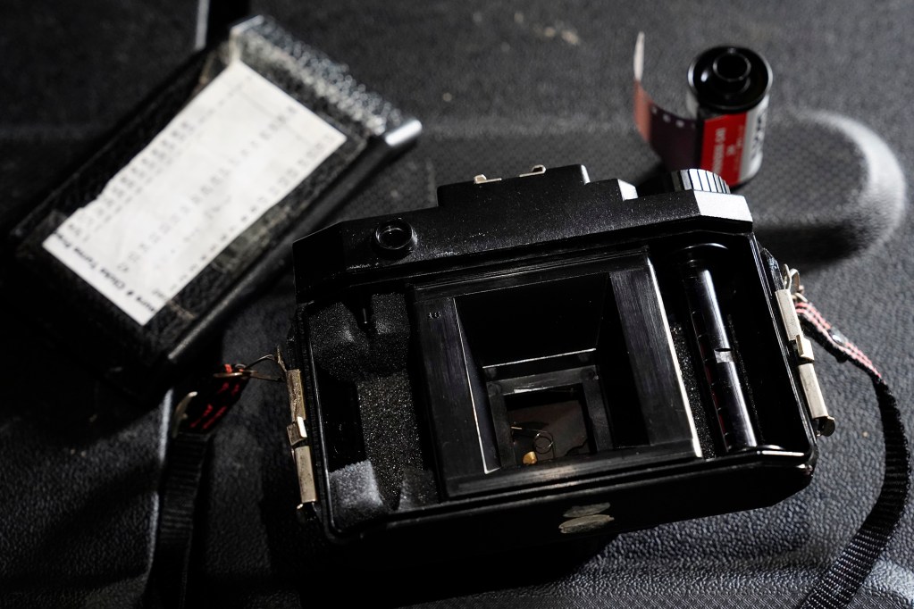 An open Holga 120 toy film camera is ready to load a roll of Ilford XP2 black-and-white 35mm film Tuesday, June 15, 2025, in ʻEwa Beach. Photographs for John Hill’s project on child abuse were made with these items. (Kevin Fujii/Civil Beat/2025)