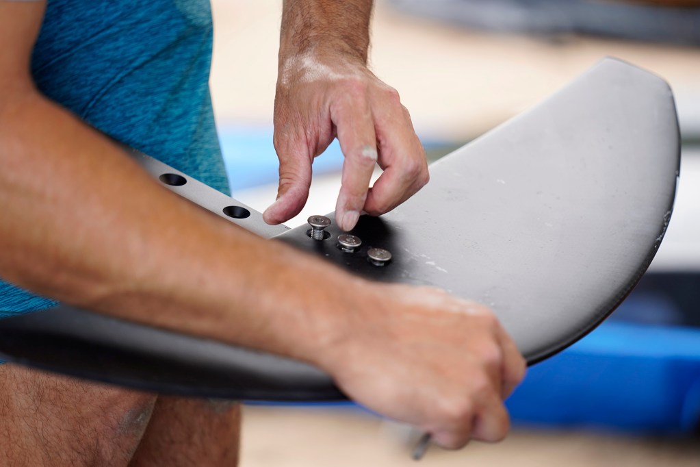 Reggie Clark attaches a front wing for an electric hydrofoil during the Hawaii Efoil Extravaganza 2025 Saturday, Aug. 9, 2025, at Ke‘ehi Lagoon in Honolulu. The first of its kind in Hawaiʻi, the day consisted of trying out e-foils and racing on a closed-circuit track for prizes. (Kevin Fujii/Civil Beat/2025)
