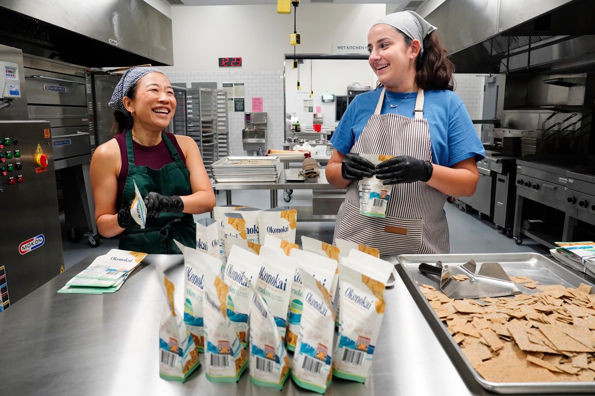 Jina Wye, from left, and her assistant Grace Gregg share a light moment while filling bags with limu crackers at the Wahiawā Value-Added Product Development Center Wednesday, Sept. 17, 2025, in Wahiawā. The center makes producing her “Made in Hawaiʻi” crackers easier with facilities and amenities usually owned by mass-production companies. (Kevin Fujii/Civil Beat/2025)