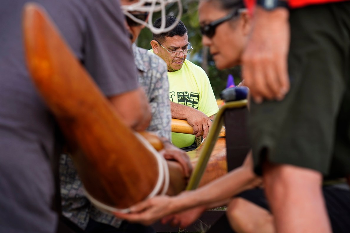 Ryan Olivares lanalana, or attaches the ama (outrigger float) to the ‘iako  (boom), to prepare Prince Prince Jonah Kūhiō Kalanianaʻole’s racing canoe, the A‘a, at Ke‘ehi Lagoon Friday, Nov. 7, 2025, in Honolulu. (Kevin Fujii/Civil Beat/2025)