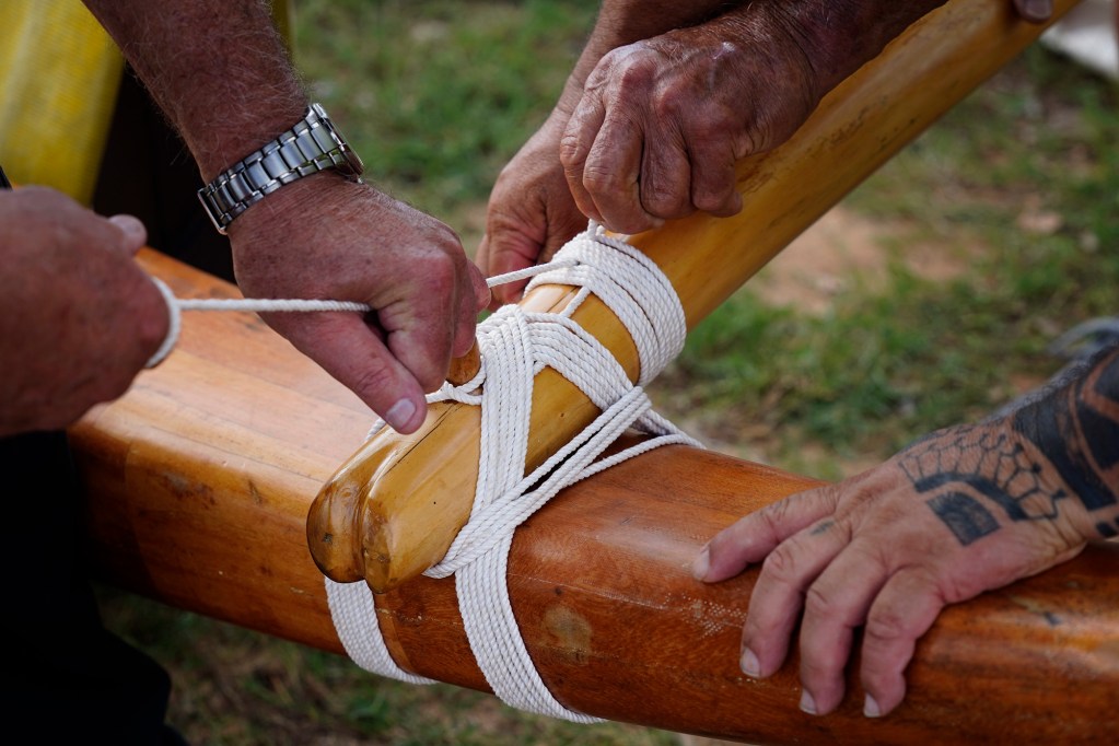 Lanalana, or attaching the ama (outrigger float) to the ‘iako  (boom), prepares Prince Prince Jonah Kūhiō Kalanianaʻole’s racing canoe, the A‘a, at Ke‘ehi Lagoon Friday, Nov. 7, 2025, in Honolulu. (Kevin Fujii/Civil Beat/2025)