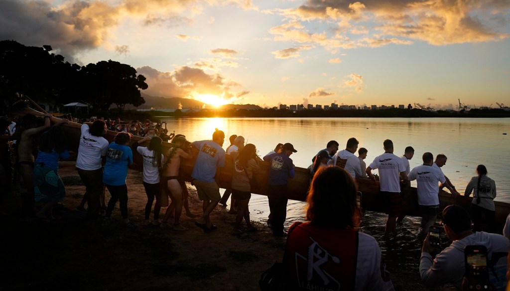The sun breaks the horizon as Prince Jonah Kūhiō Kalanianaʻole’s famous koa racing canoe named the A‘a returns to the ocean Saturday, Nov. 8, 2025, in Honolulu. (Kevin Fujii/Civil Beat/2025)