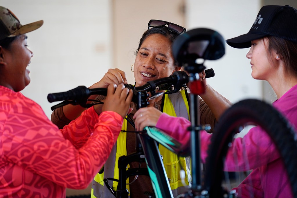 Bayer employees Ambrosialynn Casil-Dudoit, from left, Iponohea Nahoopii-Kaauwai and Keeya Bicoy attach handlebars onto a bike during Jim Falk’s annual Christmas Kids Bike Build Wednesday, Dec. 10, 2025, in Kaunakakai, Molokaʻi. Approximately 450 new bicycles are built and will distributed to keiki in Maui County. (Kevin Fujii/Civil Beat/2025)