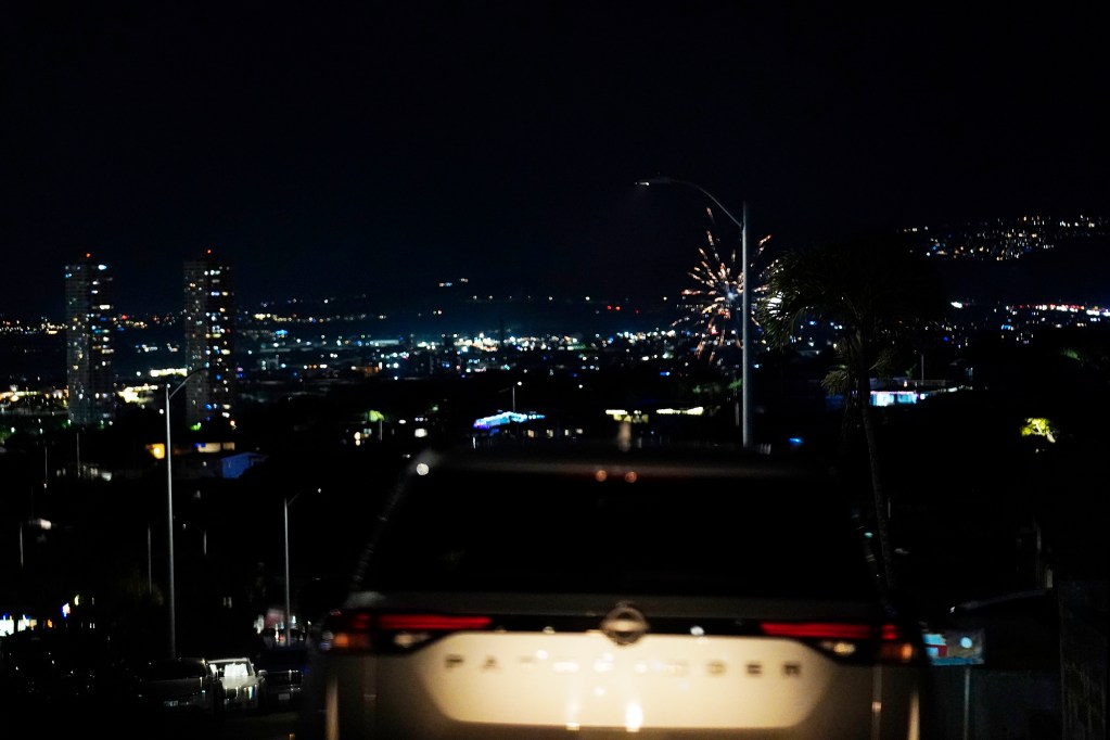 A vehicle with Department of Law Enforcement Director Mike Lambert and journalists get a lofty view of aerial fireworks launching Wednesday, Dec. 31, 2025, from Pearl City. New laws, the use of aerial drones and citizens heeding the dangers of fireworks noticeably  curbed the annual personal pyrotechnics. (Kevin Fujii/Civil Beat/2025)