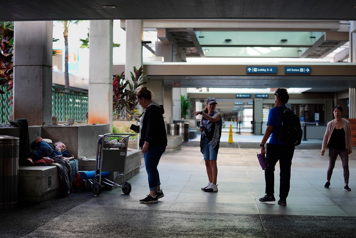 Michael Warden, from left, sleeps at the Daniel K. Inoyue International Airport terminal 2 departure area as IHS’ Sarah Rodrigues, Jo, Tiare Akana and executive director Connie Mitchell work their way through the airport during the Point In Time homeless count Monday, Jan. 26, 2026, in Honolulu. (Kevin Fujii/Civil Beat/2026)