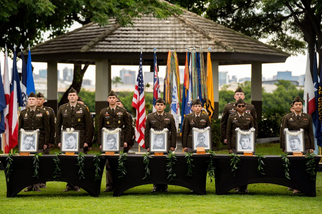 U.S. Army soldiers stand behind framed photos of former University of Hawaii ROTC cadets during a moment of silence during a posthumous commissioning ceremony at Ke'ehi Lagoon Memorial Park, Monday, Jan. 26, 2026, in Honolulu. (AP Photo/Mengshin Lin)
