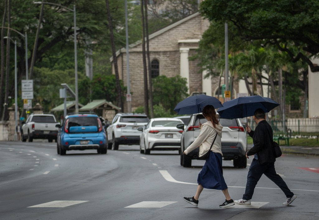 Visitors cross King St to Iolani Palace Monday, Feb. 9, 2026. Stormy weather closed governement offices, the Palace and schools today. (Craig Fujii for Civil Beat)