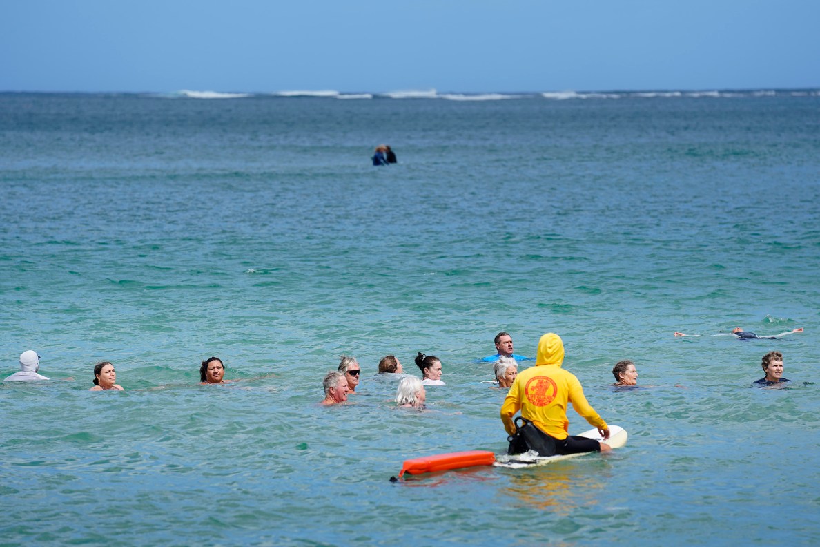 Ocean safety educator Bruce “Hoppo” Hopkins of Australia, center wearing blue rashguard, instructs rip-current clinic participants to look at the shore to see how far the rip current moved them at Waiʻoli Beach Park Wednesday, Feb. 18, 2026, in Hanalei. This rip current debunks the previous belief to swim parallel to shore if a rip moves you from your starting point. Hopkins stresses floating instead of swimming. By floating, the swimmer saves valuable energy and allows the current to move them to a safer place where they can self rescue or make rescue by a lifeguard safer. (Kevin Fujii/Civil Beat/2026)