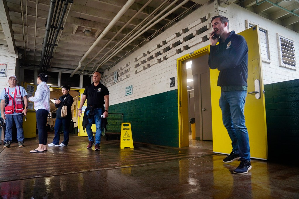 Honolulu Councilmember Matt Weyer, right, works the phone as North Shore residents evacuate to Leilehua High School after a Kona Low storm flooded Haleʻiwa and Waialua Friday, March 20, 2026, in Wahiawā. (Kevin Fujii/Civil Beat/2026)