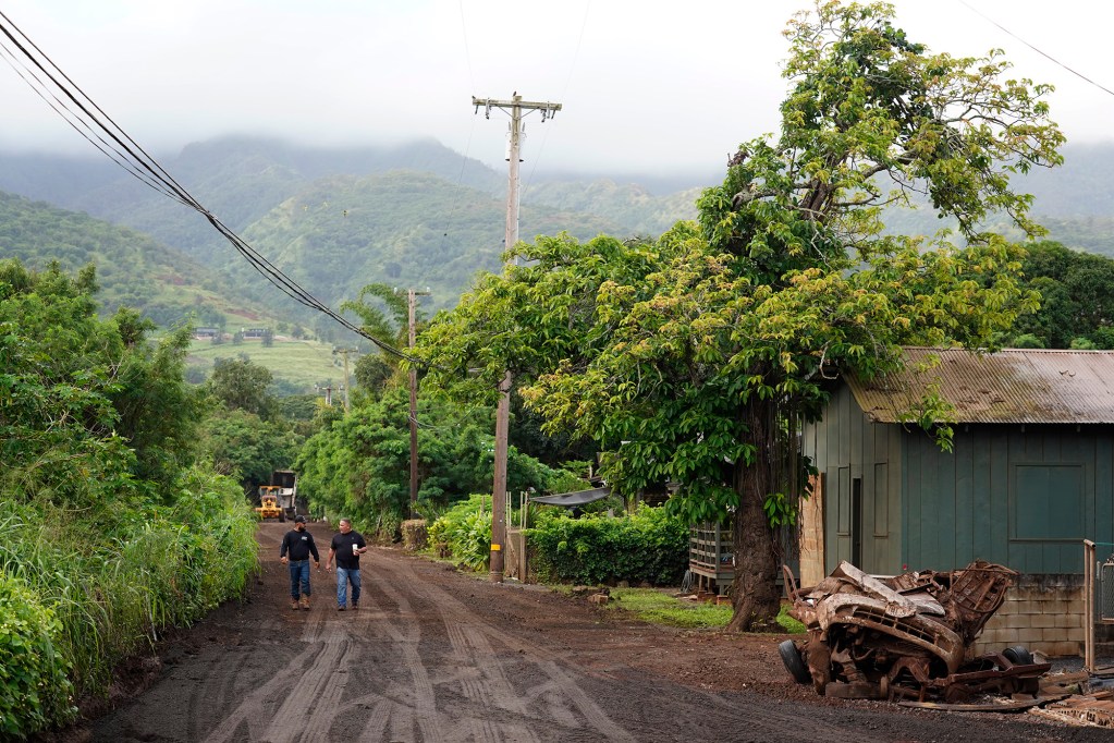 Community leader Levi Rita, left, and Deputy Director Facility Maintenance Warren Mamizuka walk out of Otake Camp Wednesday, March 25, 2026, in Waialua. The former plantation residential neighborhood received damage from the second Kona Low storm. (Kevin Fujii/Civil Beat/2026)