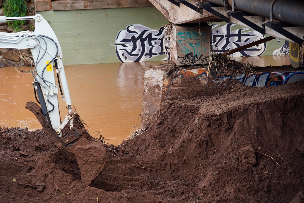 A privately owned compact excavator works to remove silt blocking a Kaukonahua Stream channel under the Otake Bridge Wednesday, March 25, 2026, in Waialua. (Kevin Fujii/Civil Beat/2026)