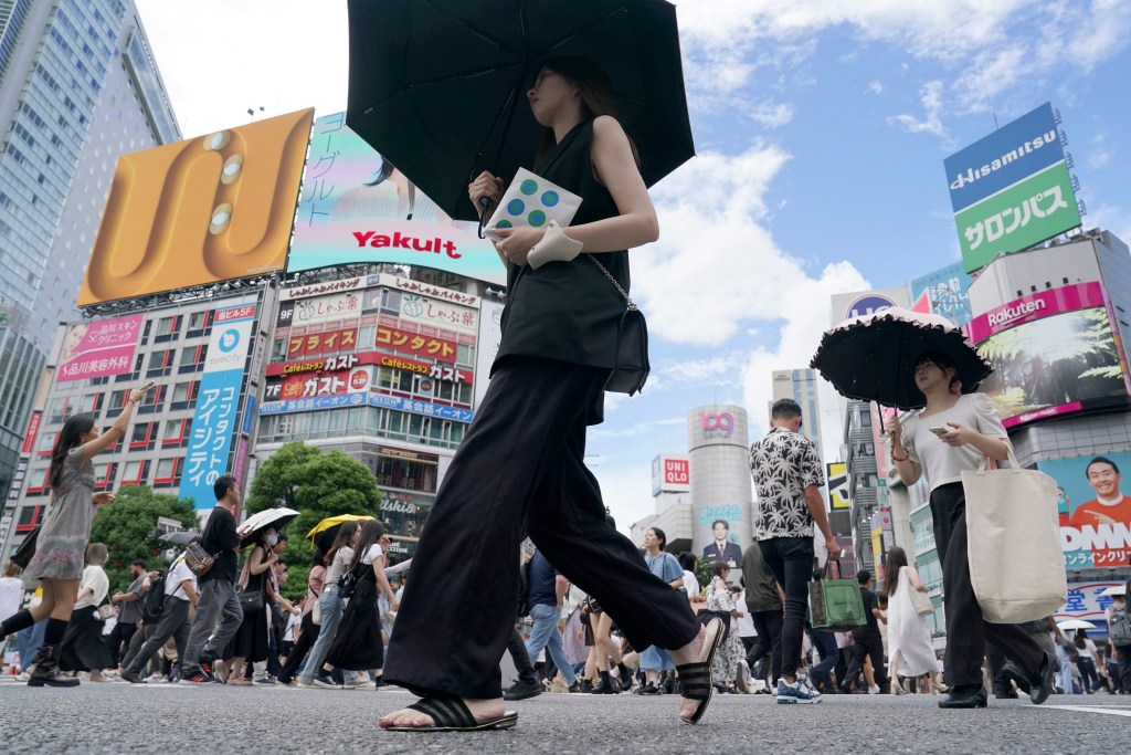 People walk along Shibuya scramble crossing under hot and sunny weather, Wednesday, Aug. 28, 2024, in Tokyo. (AP Photo/Eugene Hoshiko)