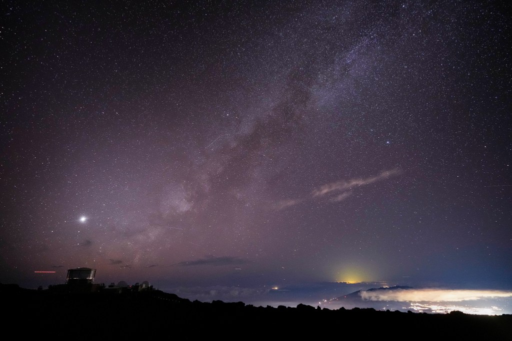 FILE - The Milky Way is seen over the Haleakala Observatory and the lights of Kahului, right, on Nov. 23, 2024, at the summit of Haleakala National Park near Kula, Hawaii. (AP Photo/Lindsey Wasson, File)