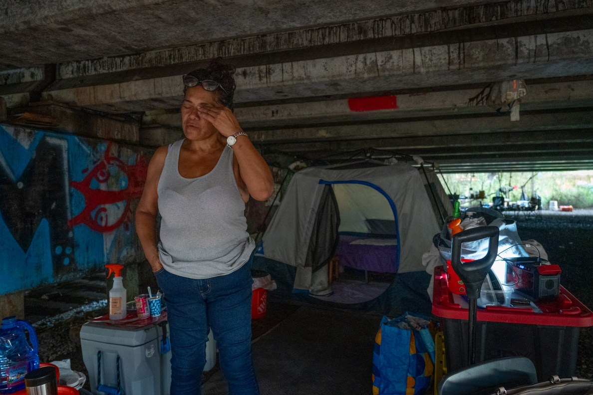 Kim Mathias rubs her face as she stands next to her tent under a bridge near the Ke'ehi Transfer Station. Mathias, 55, has been at her current location for almost one year. Originally from Hilo, Mathias suffered three strokes and has mild residual weakness and memory problems, she said.