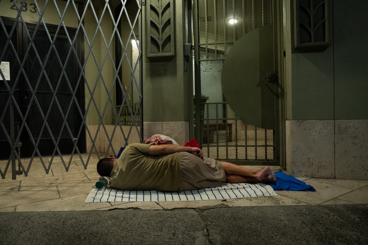 A man sleeps next to the shuttered doors of a business on Queen St.