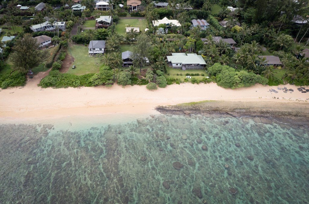 A light-colored strip of sand is seen in an aerial photograph that shows beachfront homes nestled on the shoreline.