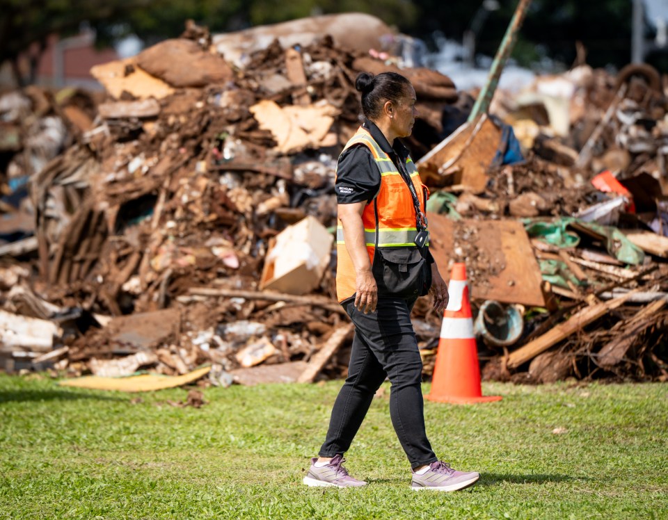 Dorreann Kaehuaea walks near a pile of debris deposited by City & County or contractor trucks at Patsy T. Mink Central Oahu Regional Park March 25, 2026. The debris is from damaged properties at Waialua and Haleiwa. (Craig Fujii/Civil Beat/2026)