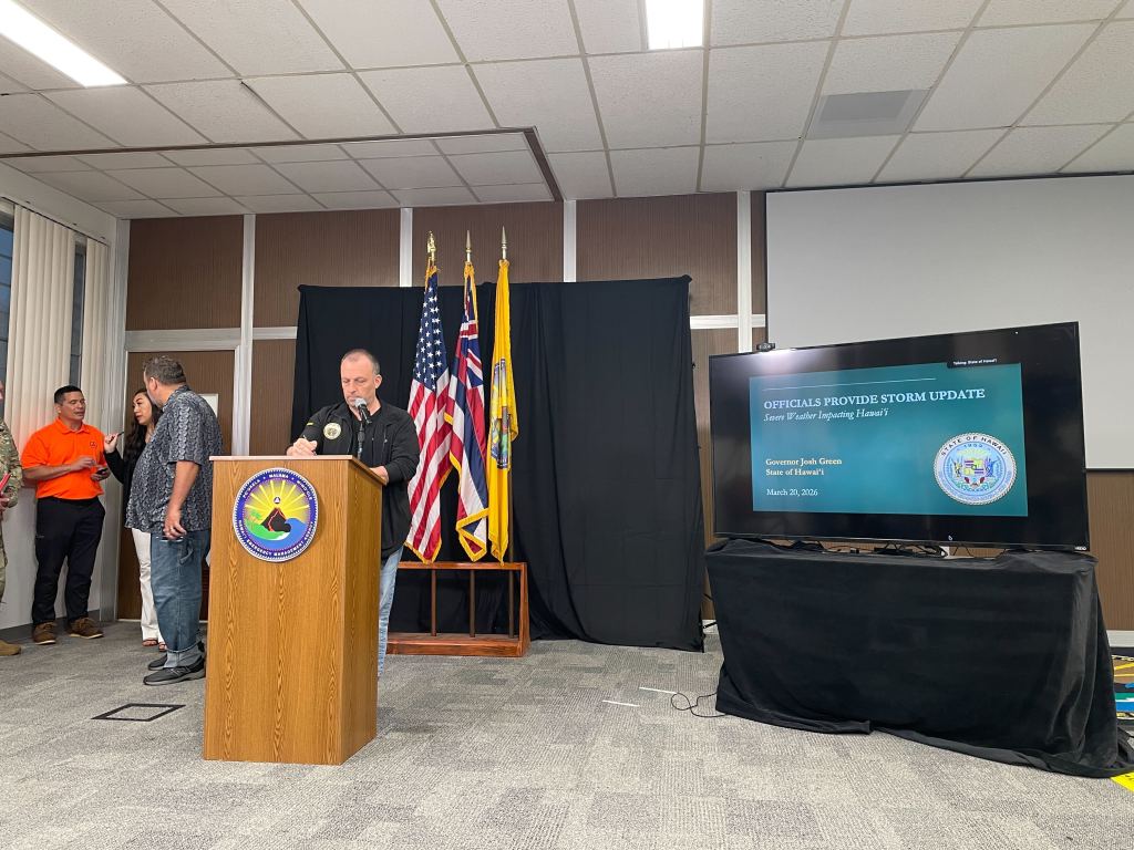 Governor Josh Green stands at a podium preparing to deliver remarks at a news conference about the recent severe Kona low storm