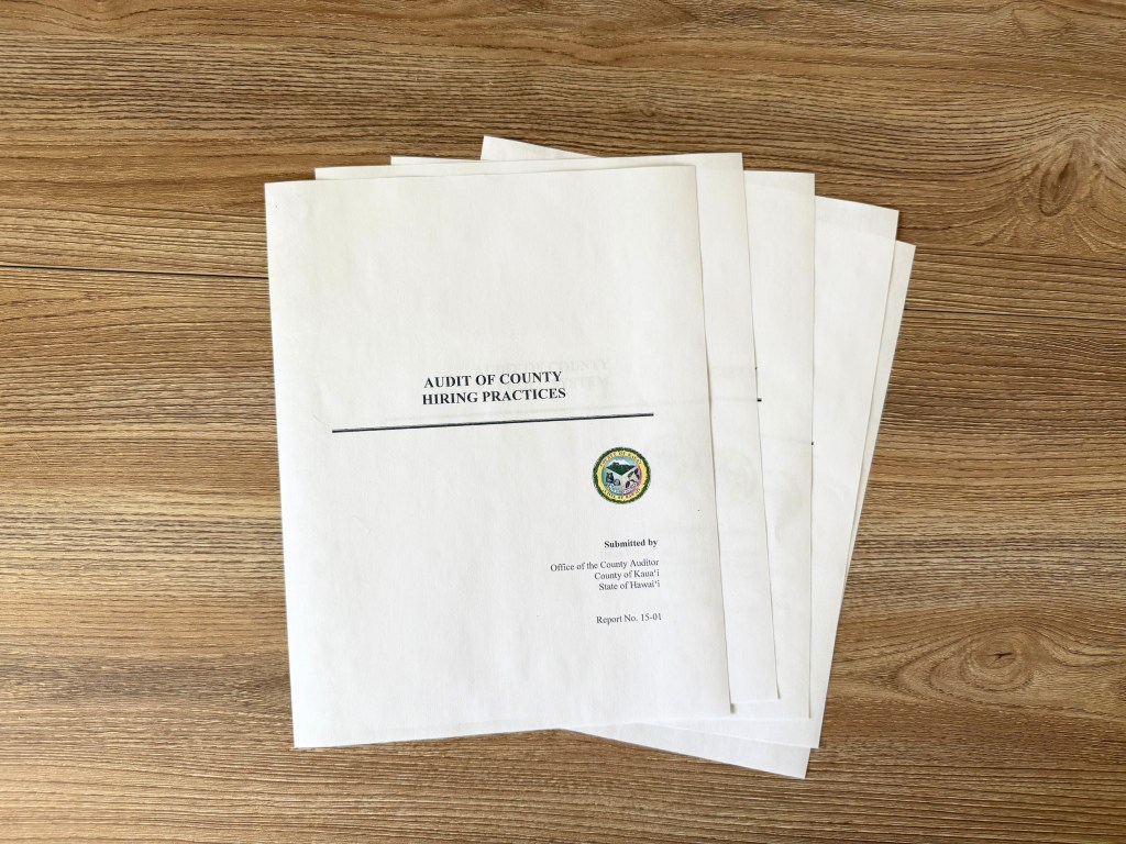A stack of papers with "Audit of County Hiring Practices" on the first page.