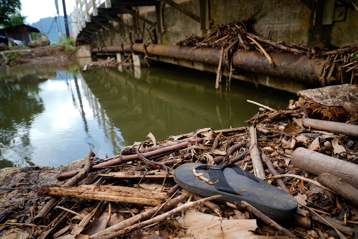 A slipper sits with debris along the Waiahole Stream’s bank at the Kamehameha Highway bridge Tuesday, April 21, 2026, in Kāneʻohe. (Kevin Fujii/Civil Beat/2026)