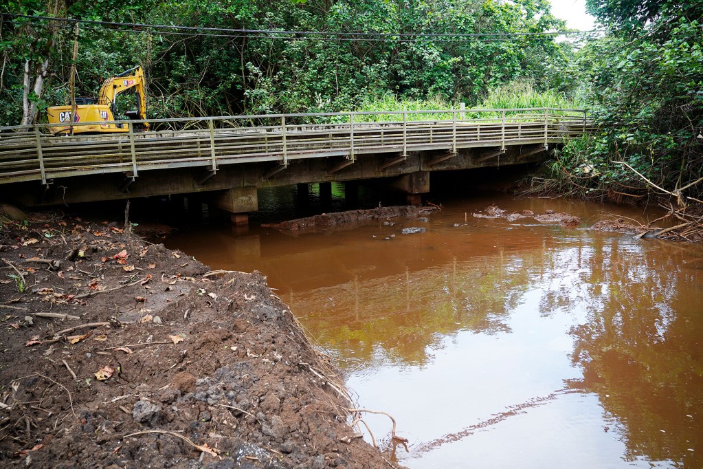 A crew under the supervision of the State of Hawaiʻi Department of Transportation clears the north bank of the  Waikāne Stream downstream of Kamehameha Highway  Tuesday, April 21, 2026, in Kāneʻohe. The crew already cleared a wide area on the upstream side of the bridge. (Kevin Fujii/Civil Beat/2026)