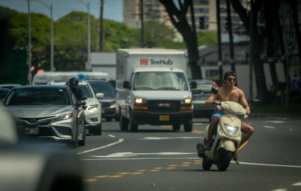 An unhelmeted moped rider turns left at Atkinson Drive from Kapiolani Blvd. March 3, 2026. (Craig Fujii/Civil Beat/2026)