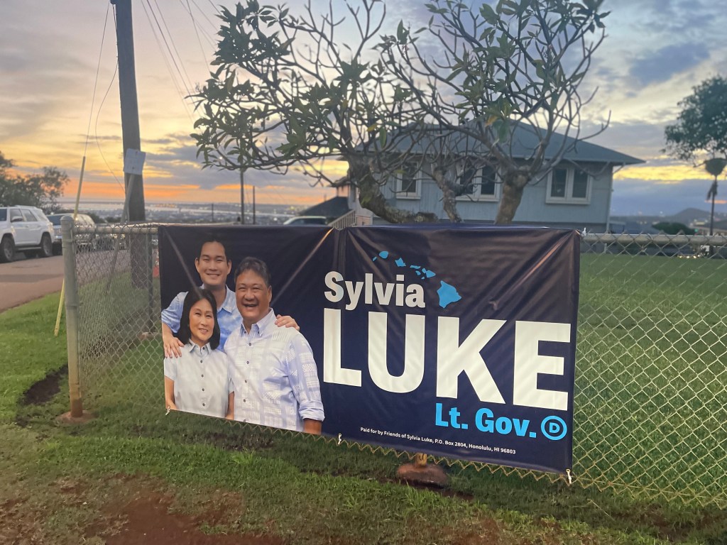 A Sylvia Luke campaign sign hangs on a fence in Alewa Heights as the sun sets in the background. Luke announced on April 19, 2026 she would exit the race.