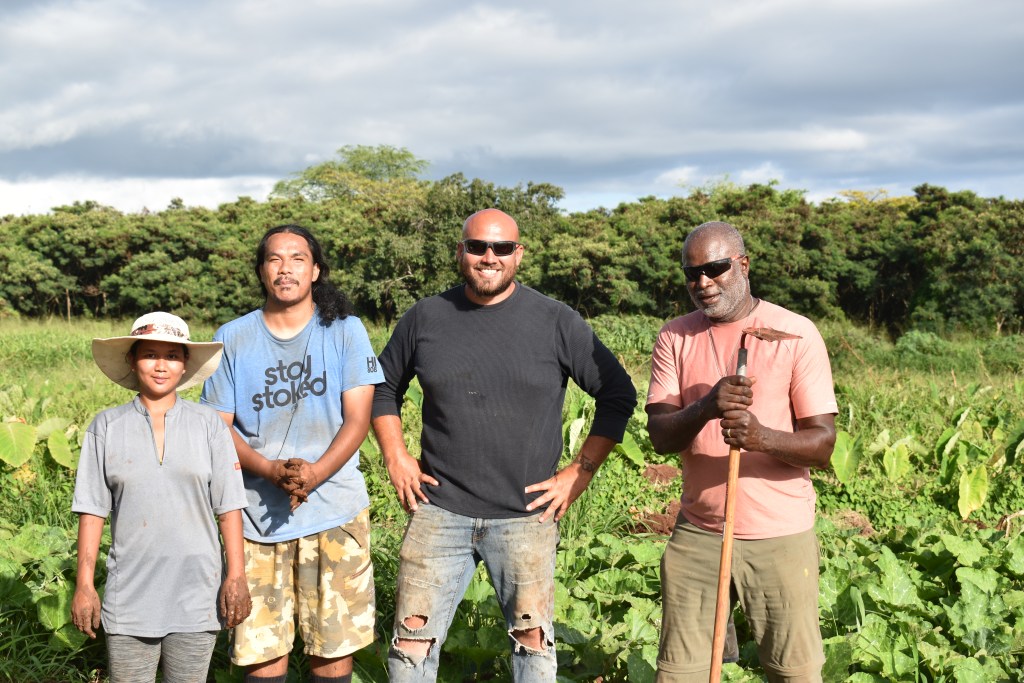 Liesel Rudolfo, Jayce Foster, Emilio Ruiz and Wil Dargan smile in front of a field of pumpkins and taro in West Kaua‘i.