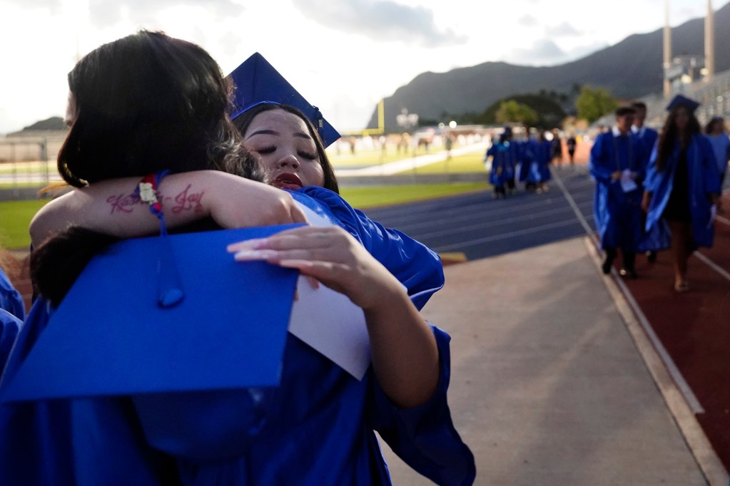 Waiʻanae High School graduate Shaiden Pham hugs a friend after their commencement ceremony Friday, May 22, 2026, in Waiʻanae. (Kevin Fujii/Civil Beat/2026)