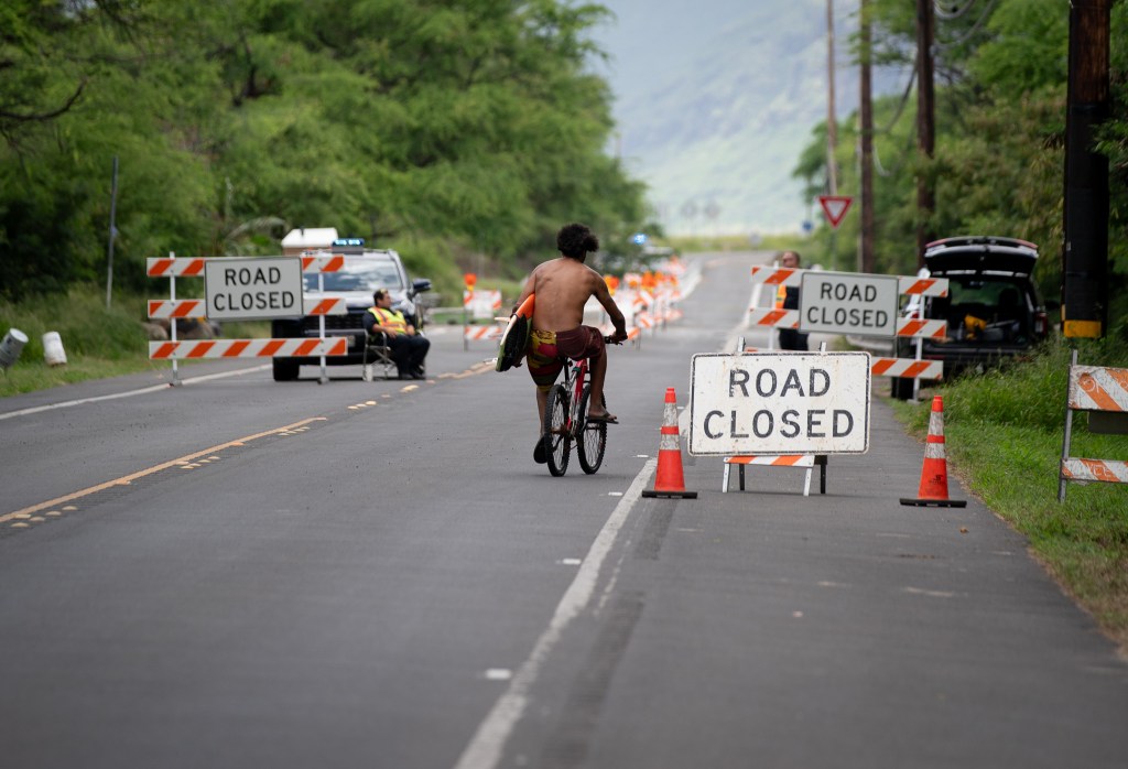 A bicyclist rides toward Waikomo bridge on Farrington Highway near Kaʻena Point, which was closed to most vehicles May 20, 2026. The bridge was damaged during the March Kona low storms. (Craig Fujii/Civil Beat/2026)