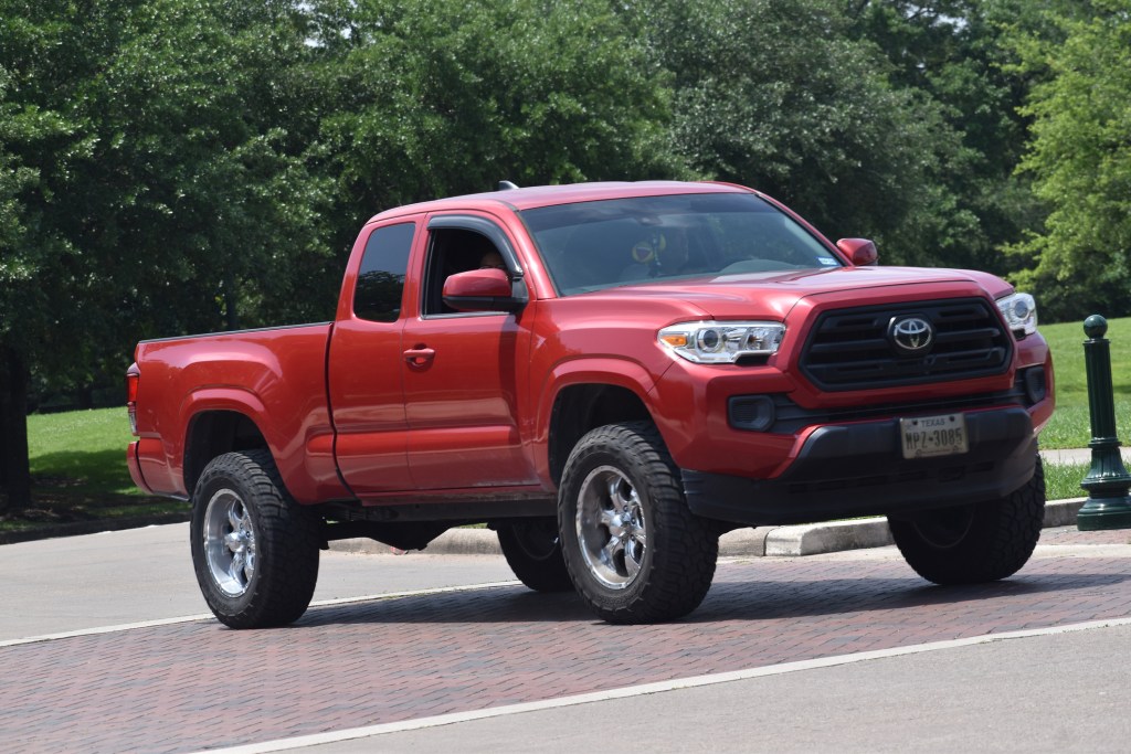 Houston, TX USA - April 29, 2024 - A red Toyota Tacoma cruising near a nature reserve