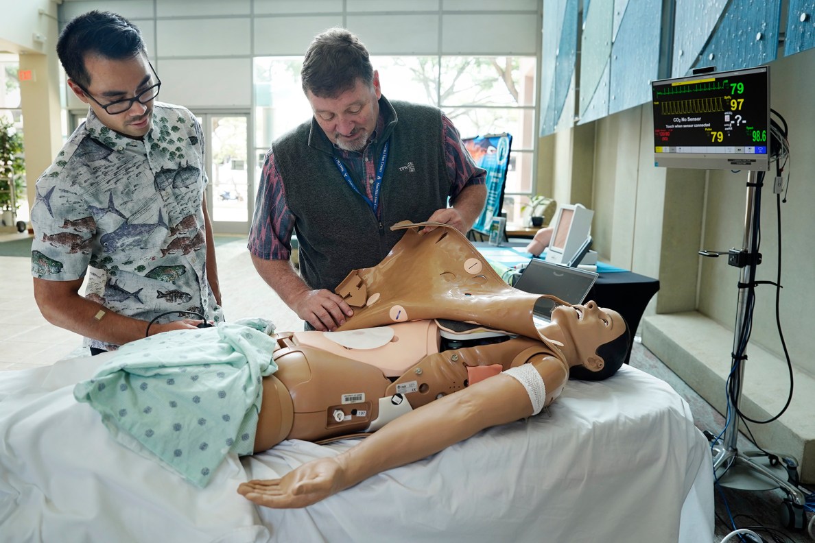 The University of Hawaiʻi John A. Burns School of Medicine 4th year student Ryan Keli‘i Shontell, left, gets a look under the skin of the new SimTiki Simulation Center’s newly acquired ultrasound “manikin” or human patient simulator with Dr. Benjamin Burg, director of simulation, Tuesday, June 23, 2026, in Honolulu. This manikin, spelled differently from mannequin which is used for modeling clothes, shows real, internal, human images programmed into the device as a medical student manipulates the ultrasound transducer. (Kevin Fujii/Civil Beat/2026)